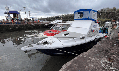 Dos barcos blancos atracados en puerto con varios turistas de fondo.