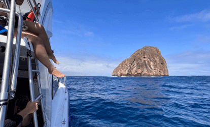 Islote visto desde un barco con varios turistas.