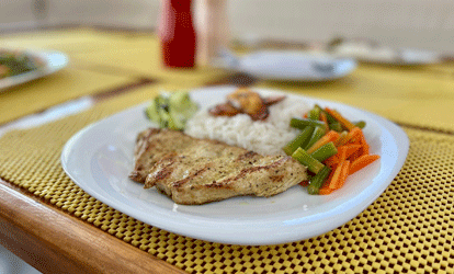 Plato de arroz con pollo a la plancha y vegetales cocidos acompañado con platano frito.